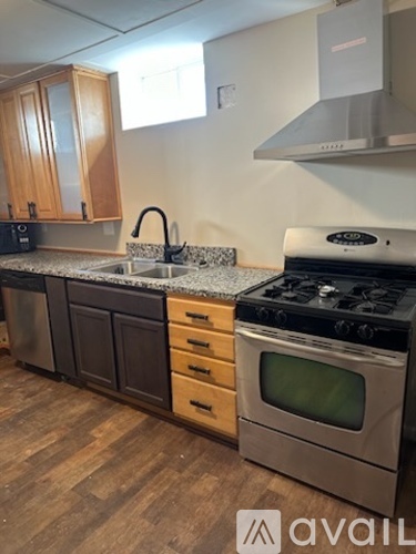 A kitchen with a stove, sink, and cabinets.