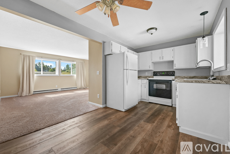 A well-lit, spacious kitchen with white appliances and a fan.