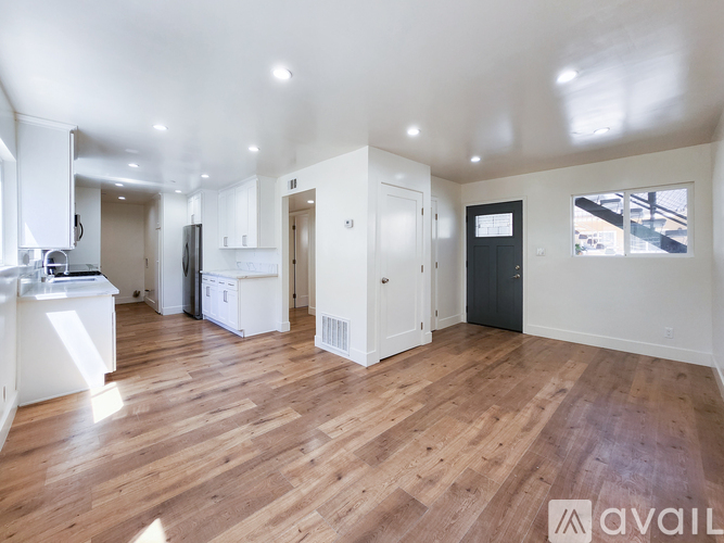A spacious room with wooden flooring and white walls.
