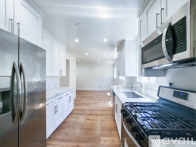 A modern kitchen with stainless steel appliances and wooden floors.