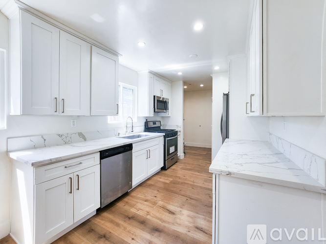 A kitchen with white cabinets and a marble countertop.