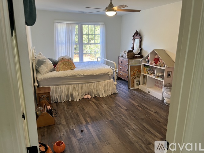 A bedroom with a bed, a dresser, and a window with curtains.