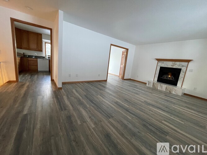 A spacious room with wooden flooring and a fireplace.