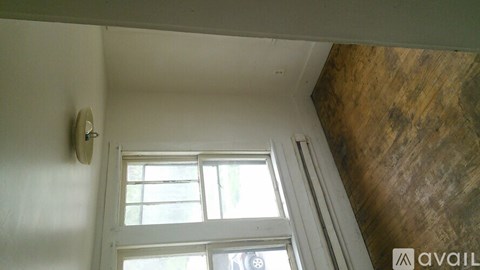 A window with white blinds in a room with a wooden ceiling.