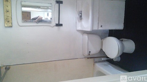 A white toilet with a white tank and a white sink in a room.