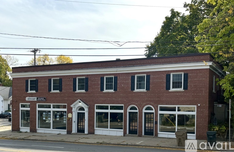 A brick building with a black awning and a sign that says "AVAILABLE".