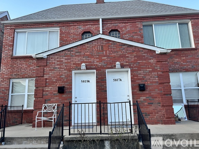 A red brick house with two white doors and a black railing.