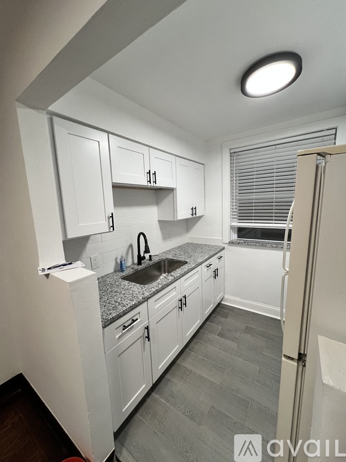 A kitchen with white cabinets and a granite countertop.