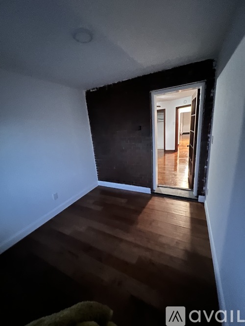 A room with wooden floors and a doorway leading to another room.