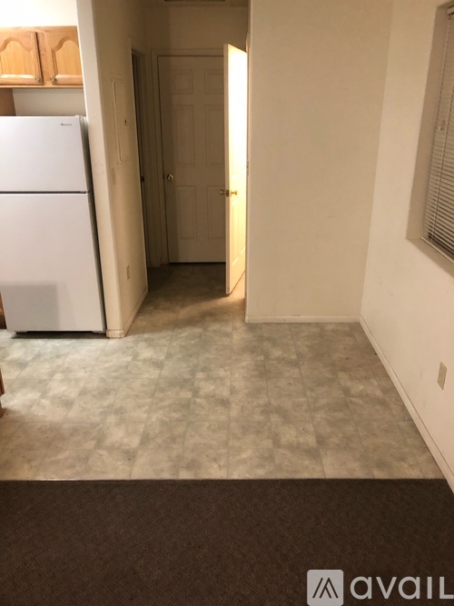 A kitchen with a white fridge and a brown rug on the floor.