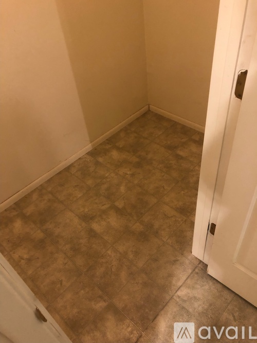 A hallway with a tiled floor and a white door.