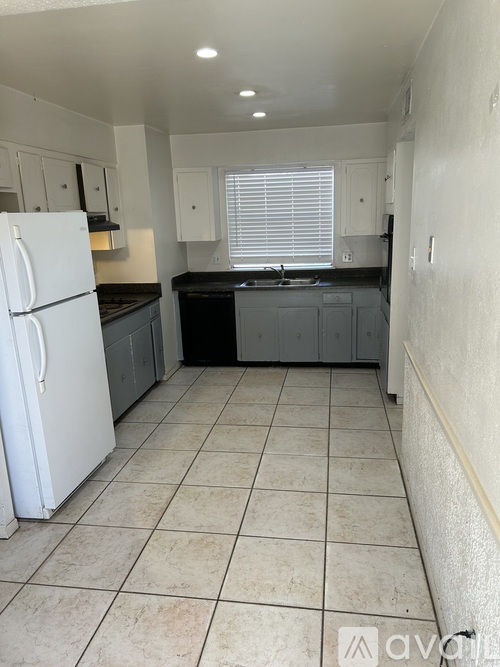 A kitchen with white appliances and black countertops.