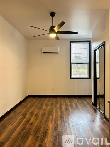 A room with a ceiling fan and wooden flooring.