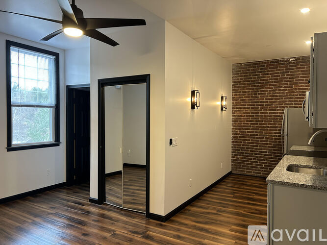 A room with a ceiling fan and a brick wall.