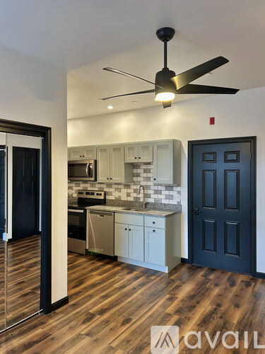 A kitchen with a black ceiling fan and wooden floors.