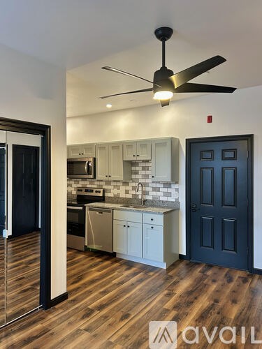 A kitchen with a black ceiling fan and wooden floors.