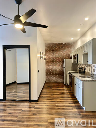 A modern kitchen with a ceiling fan and wooden floors.