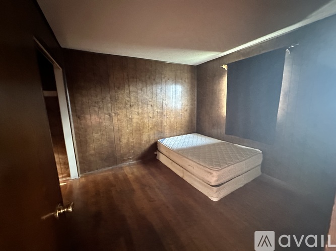 A bed with a mattress is in a room with wooden walls.