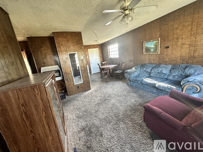 A living room with a blue couch and a ceiling fan.