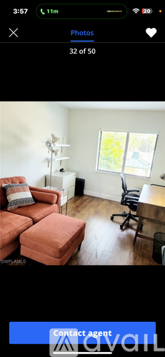 A living room with a red couch and a black office chair.