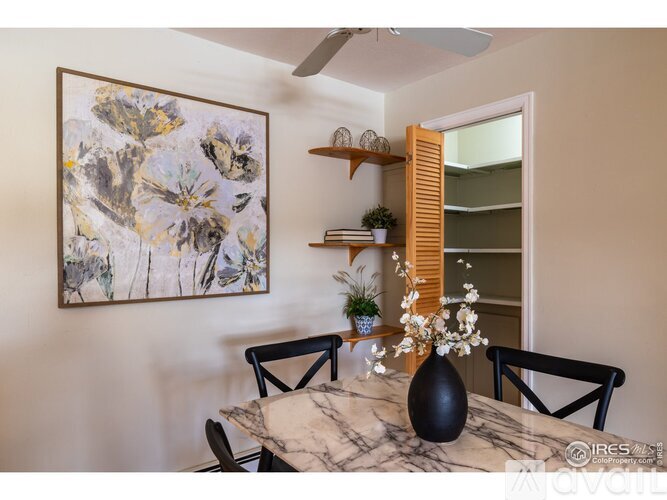 A dining room with a marble table and a large abstract painting on the wall.
