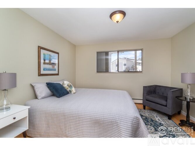 A bedroom with a bed, a nightstand, a chair, and a window.