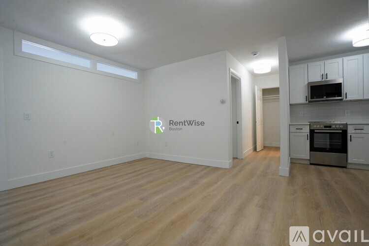 A large empty room with a kitchen area in the background.