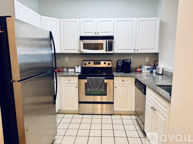 A kitchen with white cabinets and a black refrigerator.