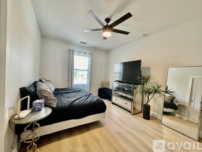 A bedroom with a bed, a television, and a ceiling fan.