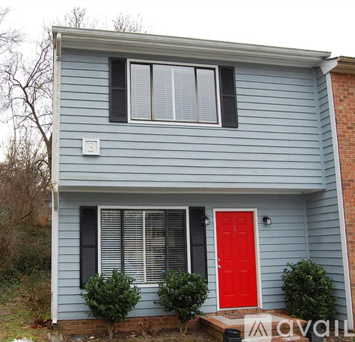 A blue house with a red door and a white light switch.