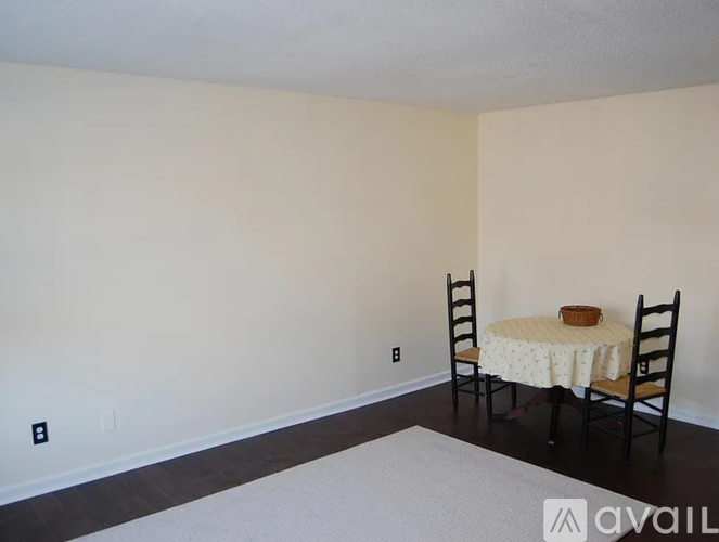 A dining room with a round table and two chairs.