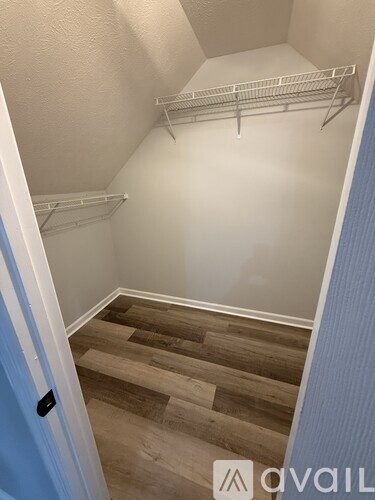 A walk-in closet with wooden floors and white shelving.