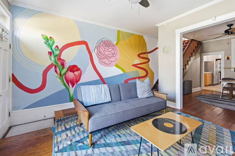 A living room with a grey couch and a colorful mural on the wall.