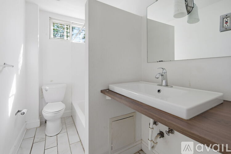 A white toilet is in a small bathroom with a sink and mirror.
