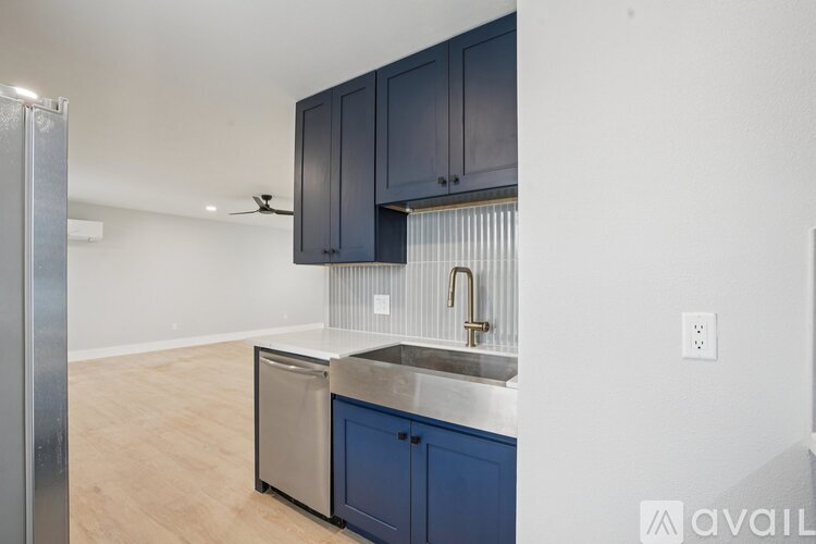 A kitchen with dark blue cabinets and a stainless steel dishwasher.