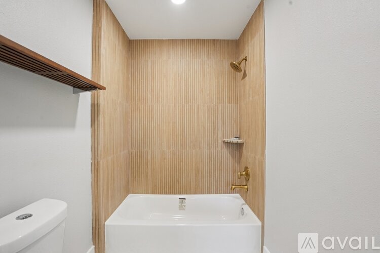 A white sink is in a small bathroom with wood paneling.