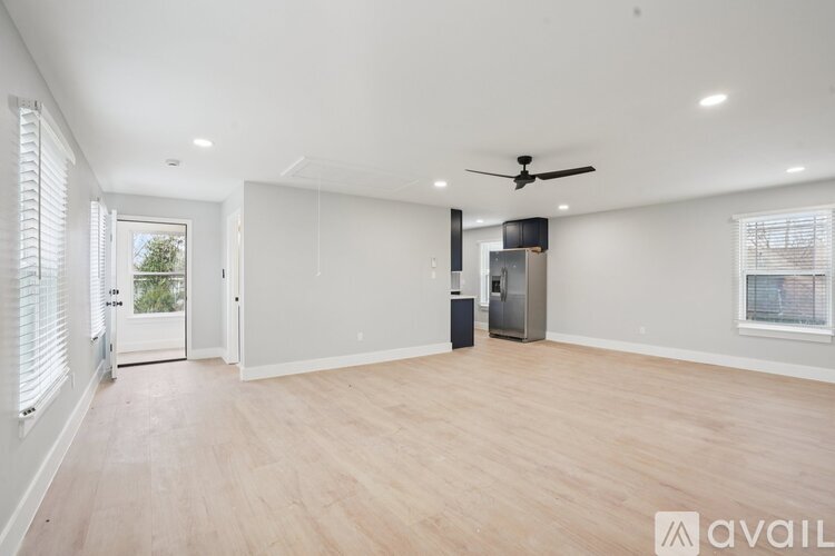 A spacious room with wooden flooring and a ceiling fan.