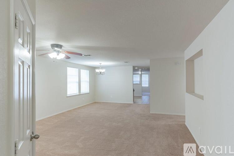 A spacious room with a ceiling fan and two windows.