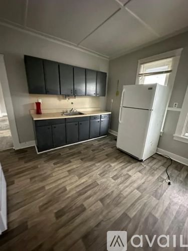 A kitchen with a white fridge and wooden flooring.