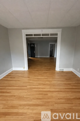 A room with wooden flooring and white walls.