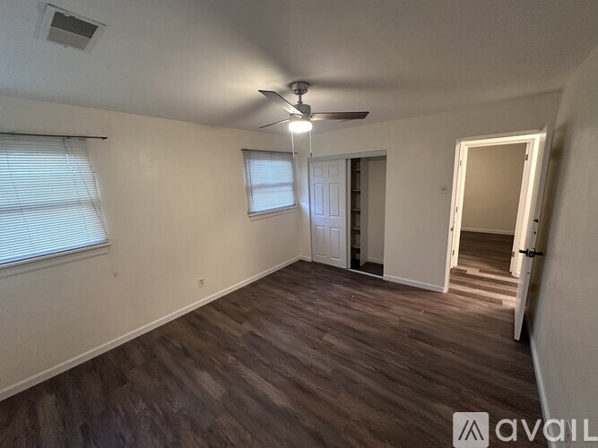 A room with a ceiling fan and wooden flooring.