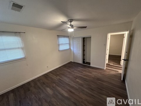 A room with a ceiling fan and wooden flooring.