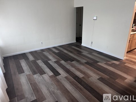 A room with wooden flooring and a white wall.