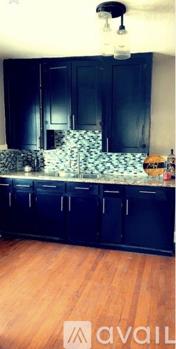 A kitchen with black cabinets and a wooden floor.