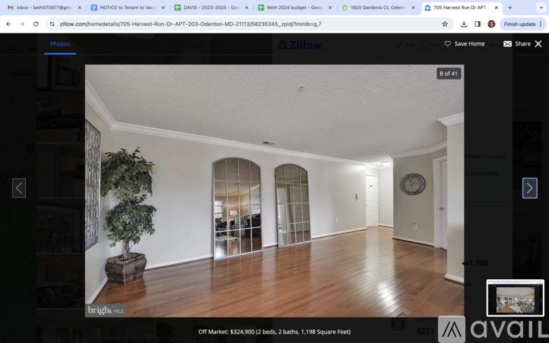A real estate website shows a photo of a spacious room with wood flooring and arched doorways.