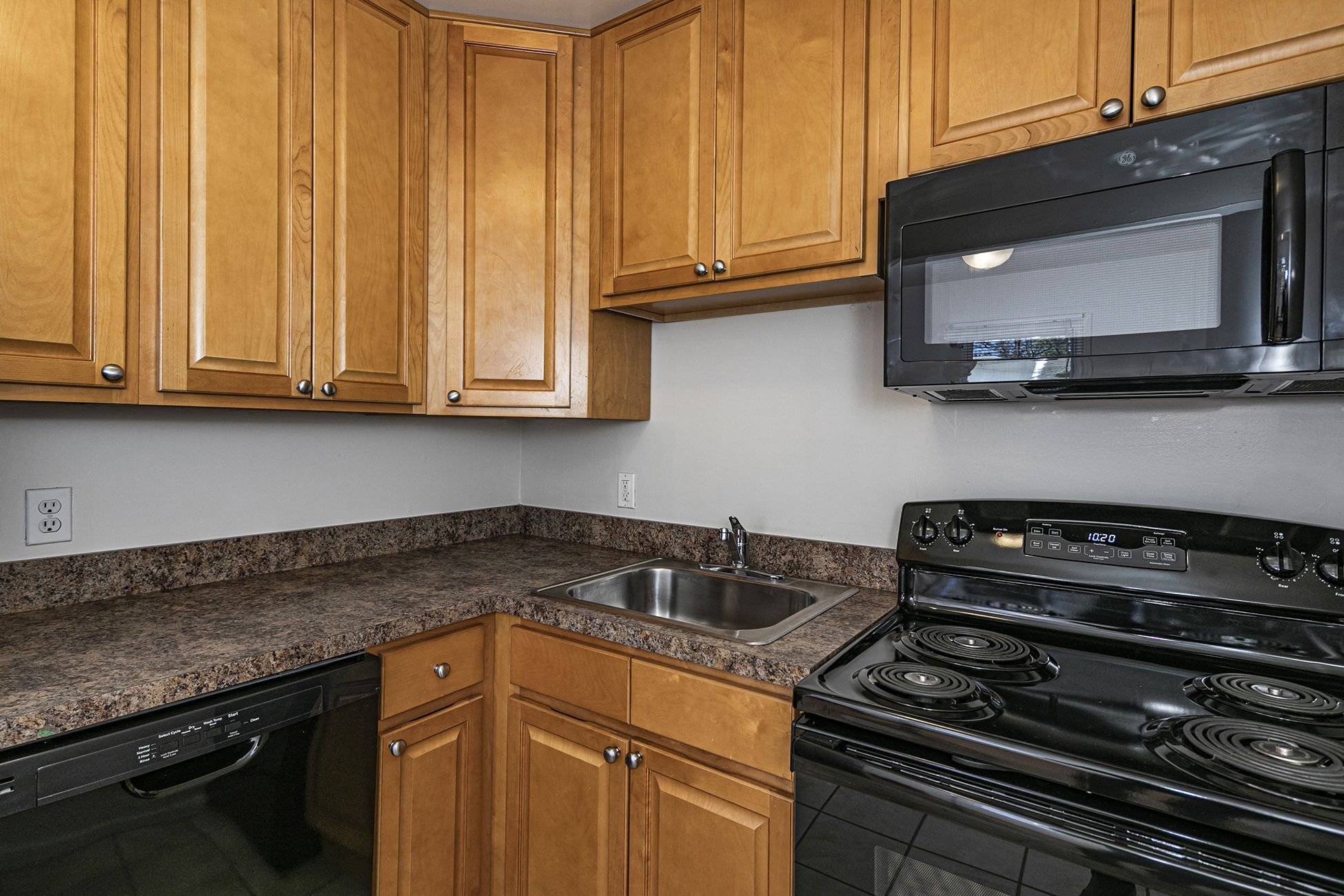 a kitchen with a stove sink and microwave and wooden cabinets