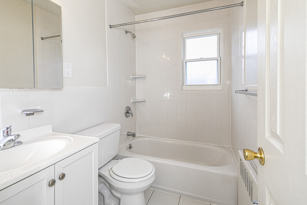 a white bathroom with a tub and a toilet and a sink