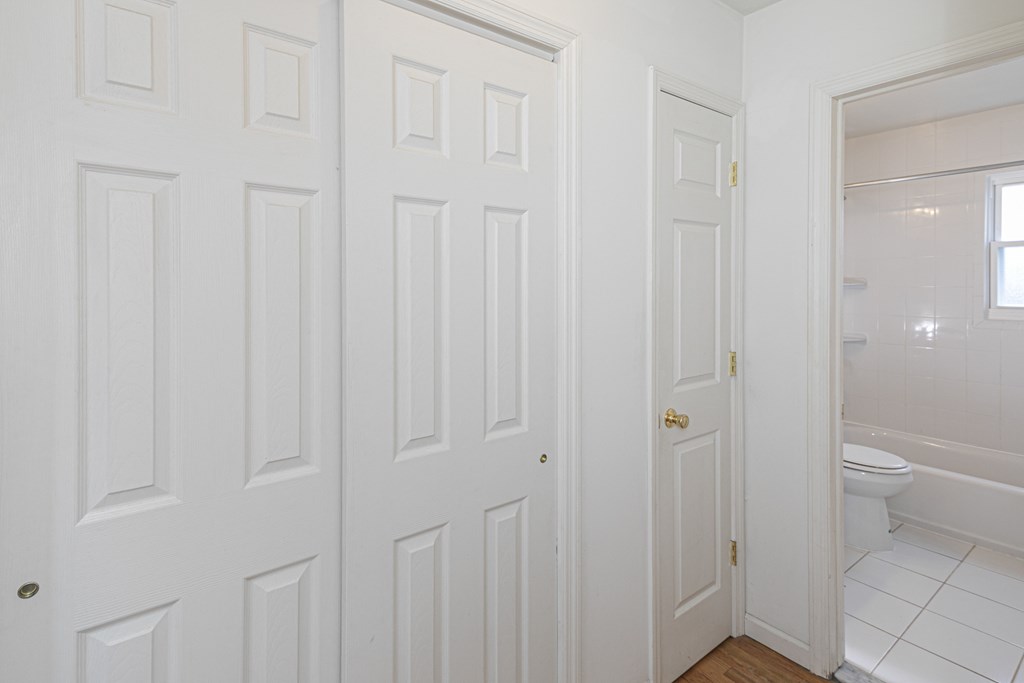 a white bathroom with two doors and a toilet