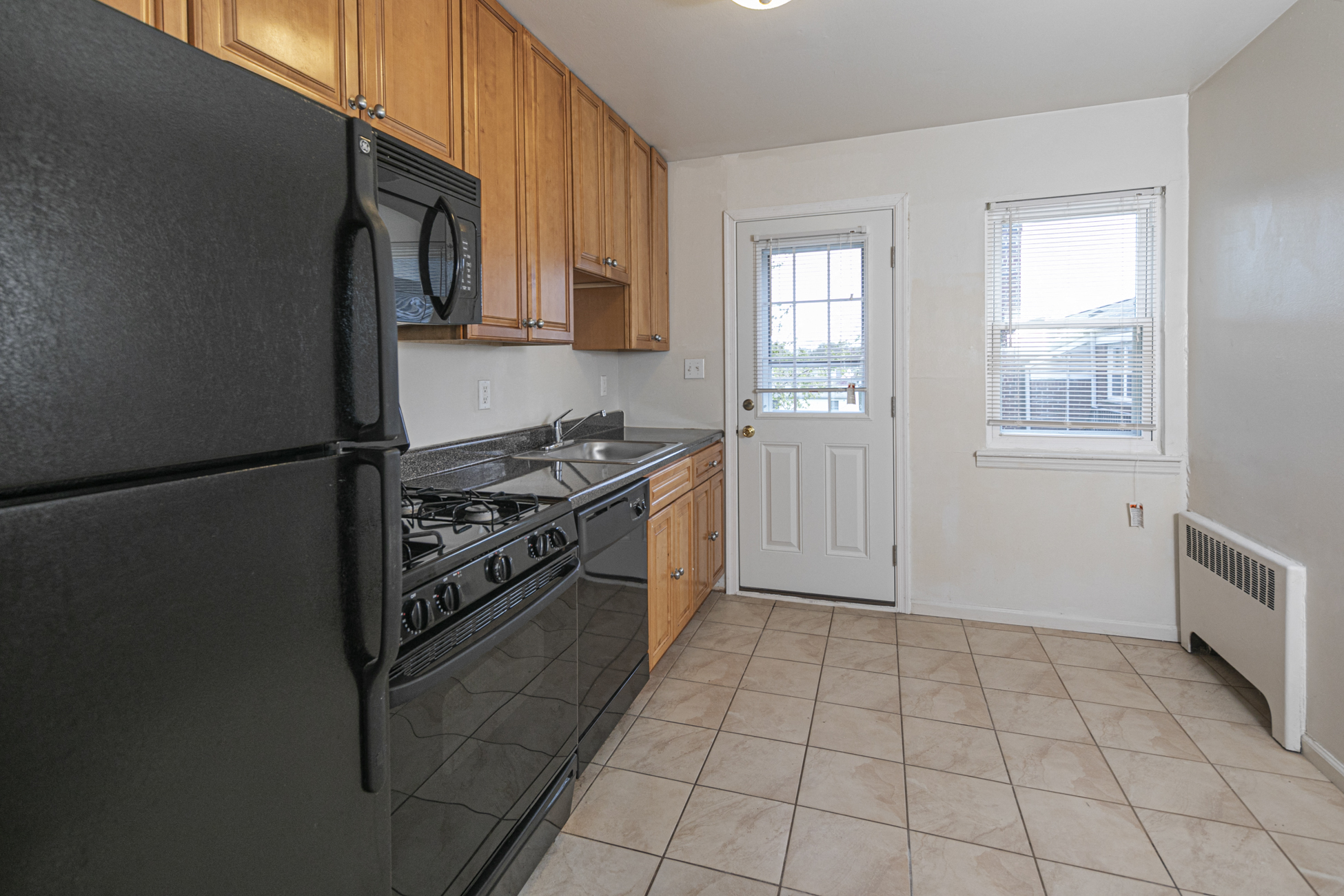 an empty kitchen with black appliances and wood cabinets