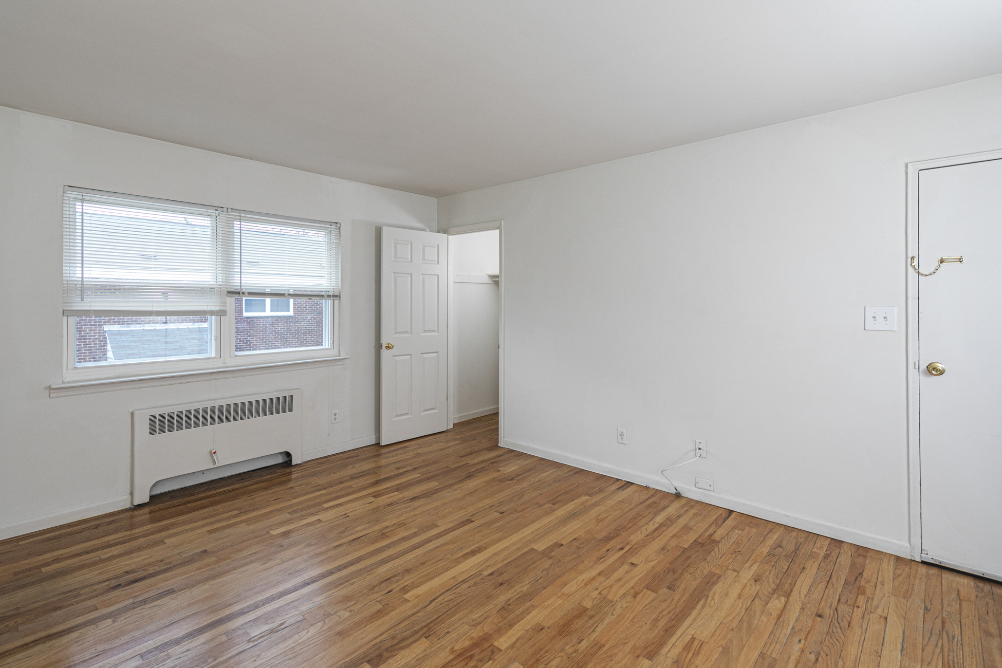 the living room of an apartment with wood floors and white walls